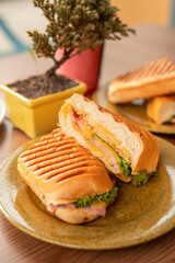 Split in half meat sandwich with ham and cheese in wooden table with decorations