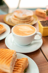 Delicious coffee cappuccino in breakfast wooden table with plants and decoration