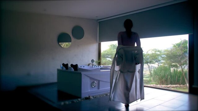 Slomo from behind of woman taking off bathrobe by jacuzzi at resort
