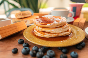 Delicious breakfast pancakes with honey and coffee in wooden table with plants and decoration