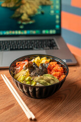 Fresh poke bowl in desktop with computer for office lunch