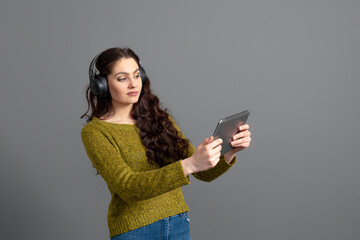 young woman with headset and tablet in hand playing games and talking to friends online