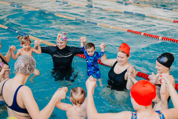 Moms and their newborns playing in pool at infant swimming class