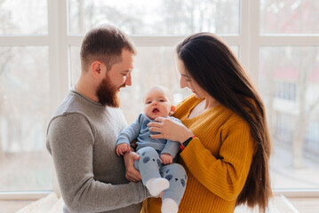 family, parenthood and people concept - happy mother, father with baby at home