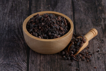 Himalayan black salt, Indian black salt or Kala namak in wooden bowl with wooden scoop on wooden table. Used in cooking, especially in Asian and Indian cuisine. Bath salt spa.