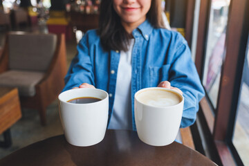 Closeup image of a young woman holding and serving two cups of hot coffee