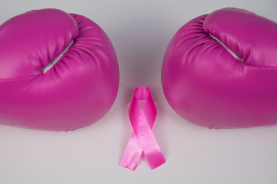 Pink boxing gloves and pink ribbon on a white background. The concept of the fight against breast cancer. 