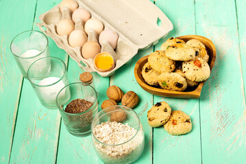 Oatmeal cookies with candied fruits in a wooden plate and ingredients for its preparation