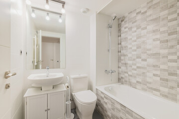 White clean bathroom with tiled tub, sink and toilet with mirror. Concept of cleanliness and simple...