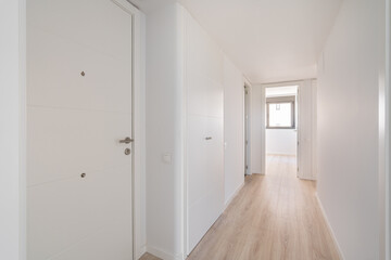 Narrow white corridor with doors and entrances to different rooms and premises and resting on a...