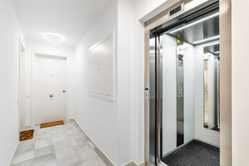 Modern reliable outdoor elevator with a view of the hall and doors to the apartments in new apartment building. Concept of convenience and high-tech urban development