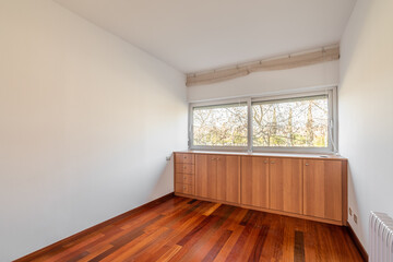 Light and compact empty room with dark wood laminate and a closet near the windows with blinds. Concept of hotel room or an empty apartment after being handed over by the developer