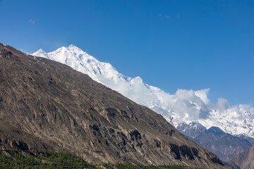 Contrasting mountains with blue sky. Barren and snow covered mountains with blue sky.