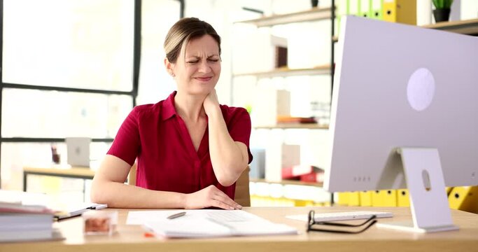 Tired unhealthy woman sitting at computer rubbing neck and feeling pain from osteochondrosis
