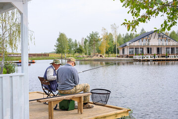 Anglers catch fish with fishing rod in specially equipped convenient place on lake. Leisure and...