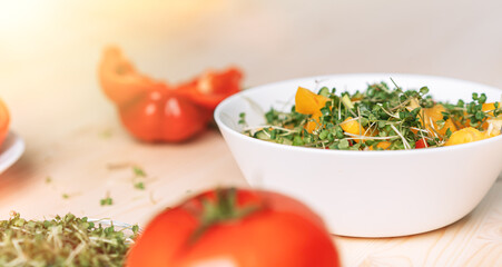 Vegetable salad with microgreens near ingredients on wooden table.