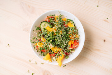 Vegetable salad with microgreens on wooden table.