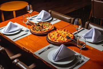Cheese and Vegetable Pizza on a wooden plate on a table in a restaurant setting