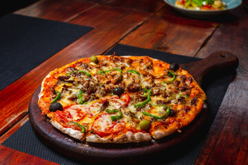 Pizza on a wood plate on a vintage table 