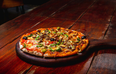 Pizza on a wood plate on a vintage table 