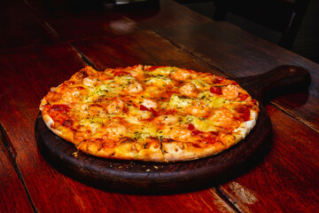 Cheese and Vegetable Pizza on a wooden plate on a table in a restaurant setting