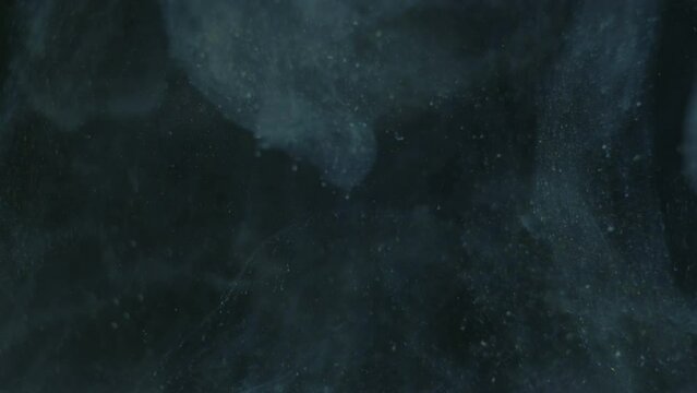 Ink In Water Real Dust Particles. Blue ink float in the in water with dust and glitter magic gold particles.
