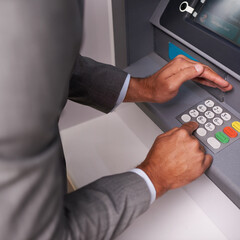 Keep your pin safe. a businessman entering his pin code at an ATM.