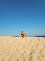 tourist girl sitting resting in the dunes of Bolonia, Cádiz