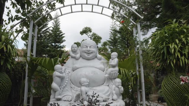 White marble sculpture of Laughing Buddha with five kids. Static shot.