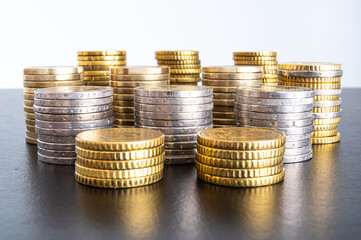 Stacks of coins next to each other, on black surface. Amount of money and wealth. 
