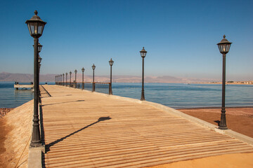 Aqaba. Breakwater with fence and wooden deck for walking. Coastline with sandy beaches. 
