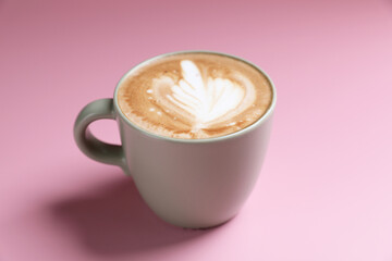 hot cappuccino with latte art isolated in pink background