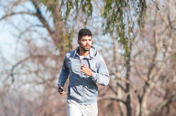 Naklejka na ściany i meble Black athlete in grey sportswear running in the park