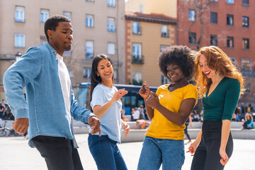 Multiethnic young friends dancing a city square, group of happy people having fun together
