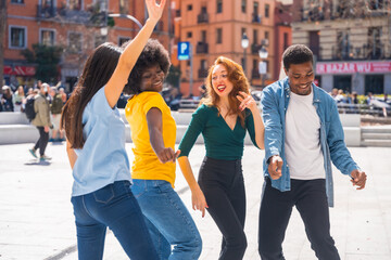 Multiethnic young friends dancing in a city square, group dancers having fun to music