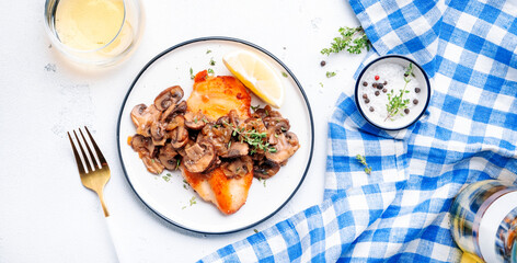 Fried chicken fillet with mushrooms and onion in white wine sauce with thyme on plate, white background, top view
