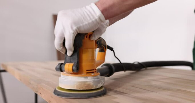 Closeup of sanding wood with orbital sander in workshop