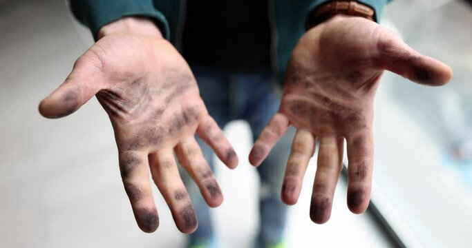 Man shows black dirty hands covered with soot