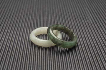 Top view of white and green jade rings on a black background