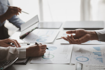 Company meeting room has businessmen and finance managers meeting together on finance topics, they are looking at information on documents and discussing together. Concept company financial management