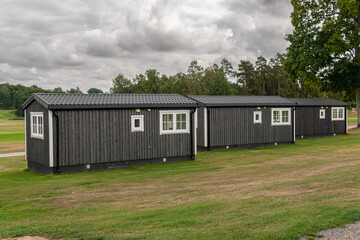 Stylish little black wooden houses in Scandinavian style near a golf course. Summer cottage, temporary housing for weekend or vacation. 