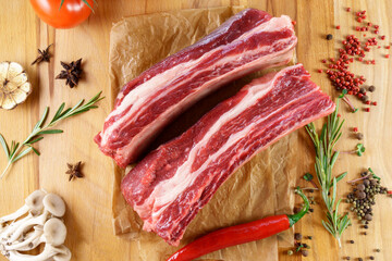 Raw Tomahawk steak on wooden background with spices. Cooking meat