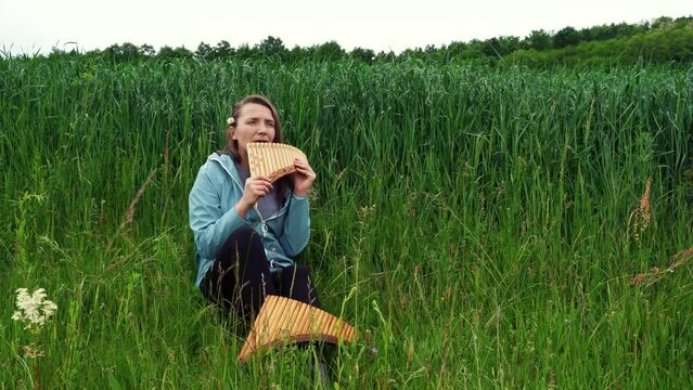 A young woman plays the panflute in nature