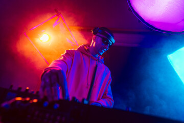 Male DJ playing music in the night club - obrazy, fototapety, plakaty