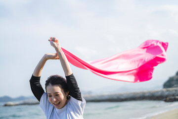 青空とピンクの布を持った女性