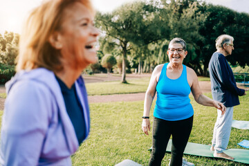 Senior sport people having fun during yoga class outdoors at park city - Focus on right woman face - Elderly community workout lifestyle concept