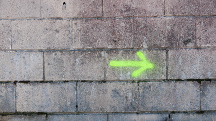 Flecha pintada con spray amarillo fluor en pared de bloques de hormigón