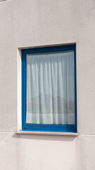 Cortina blanca en ventana moderna con marco azul