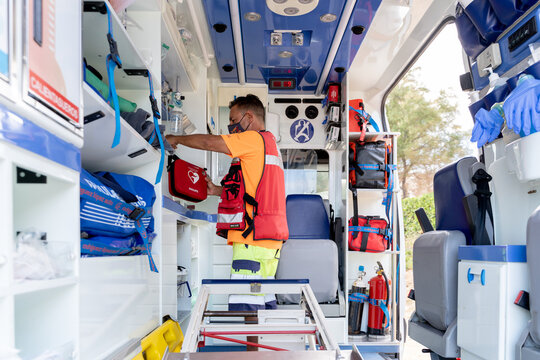 First aid worker with mask working inside an ambulance