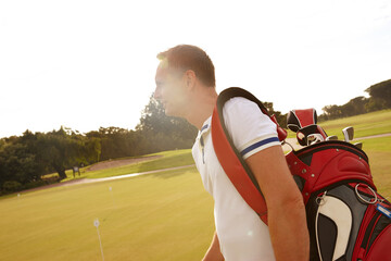 Hes on course to have a great day. a man walking on a golfing green.